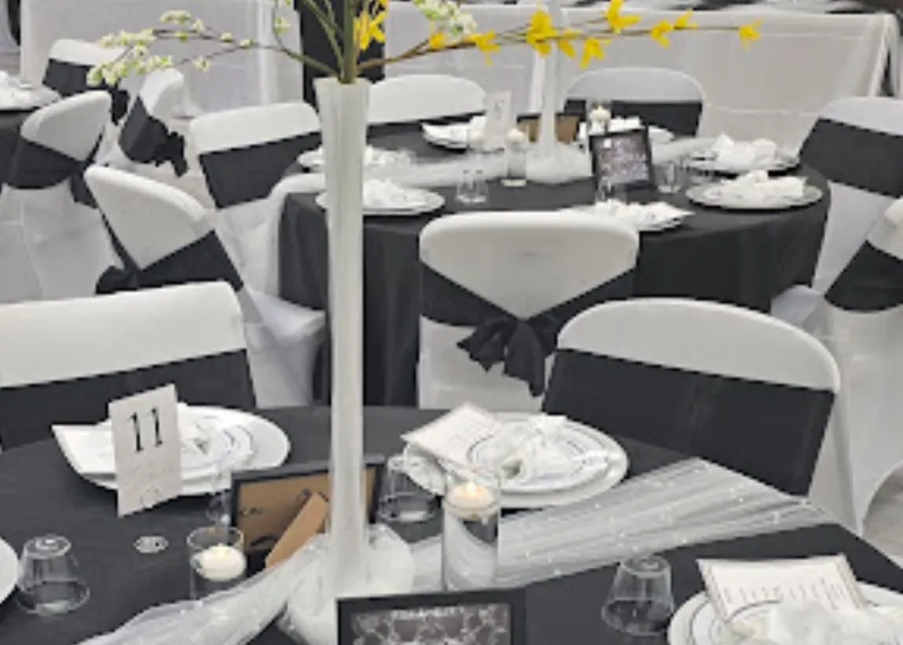 Grace Center banquet table set with black linens, white place settings and a tall floral centerpiece