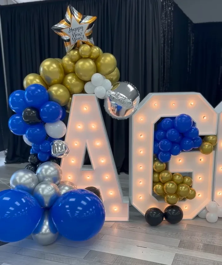 Lighted marquee letters and a blue, gold and silver balloon garland set up for a celebration at Grace Center
