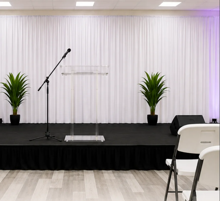 Clear podium and microphone in front of white drapes