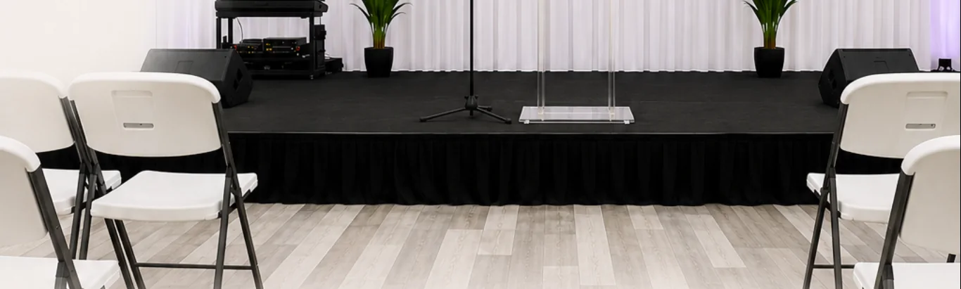 Wide view of the Grace Center hall with a podium and white chairs