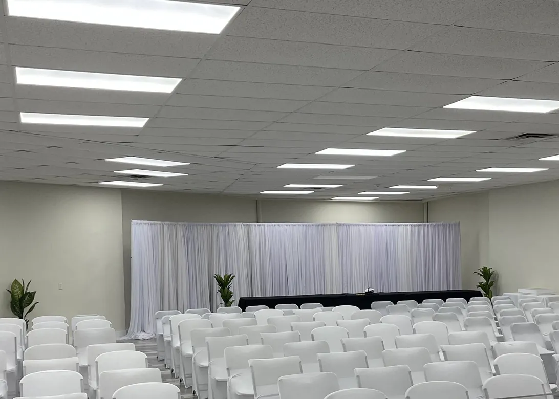 Rows of white chairs set up in the Grace Center hall facing white drapes